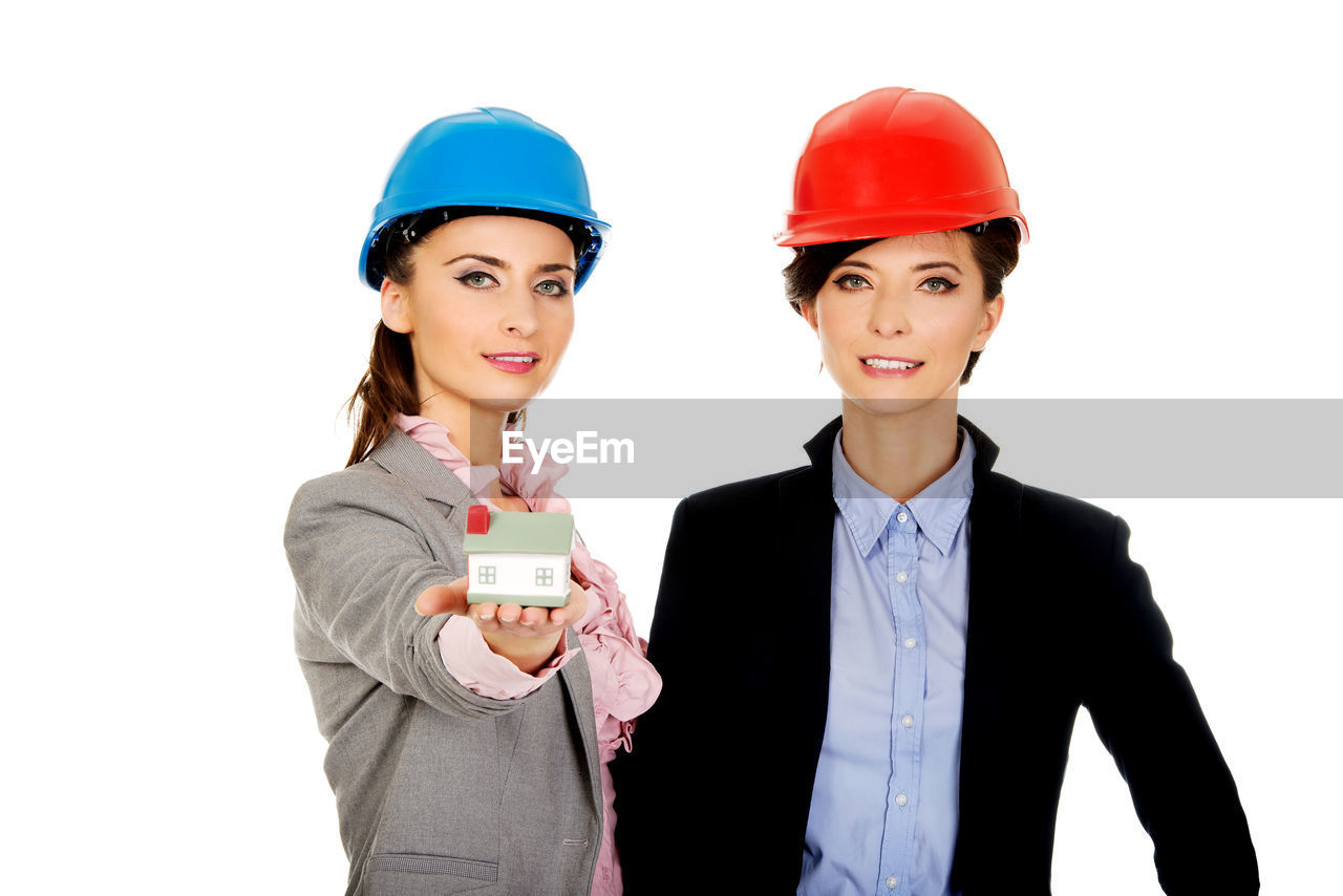 Portrait of female engineers standing against white background