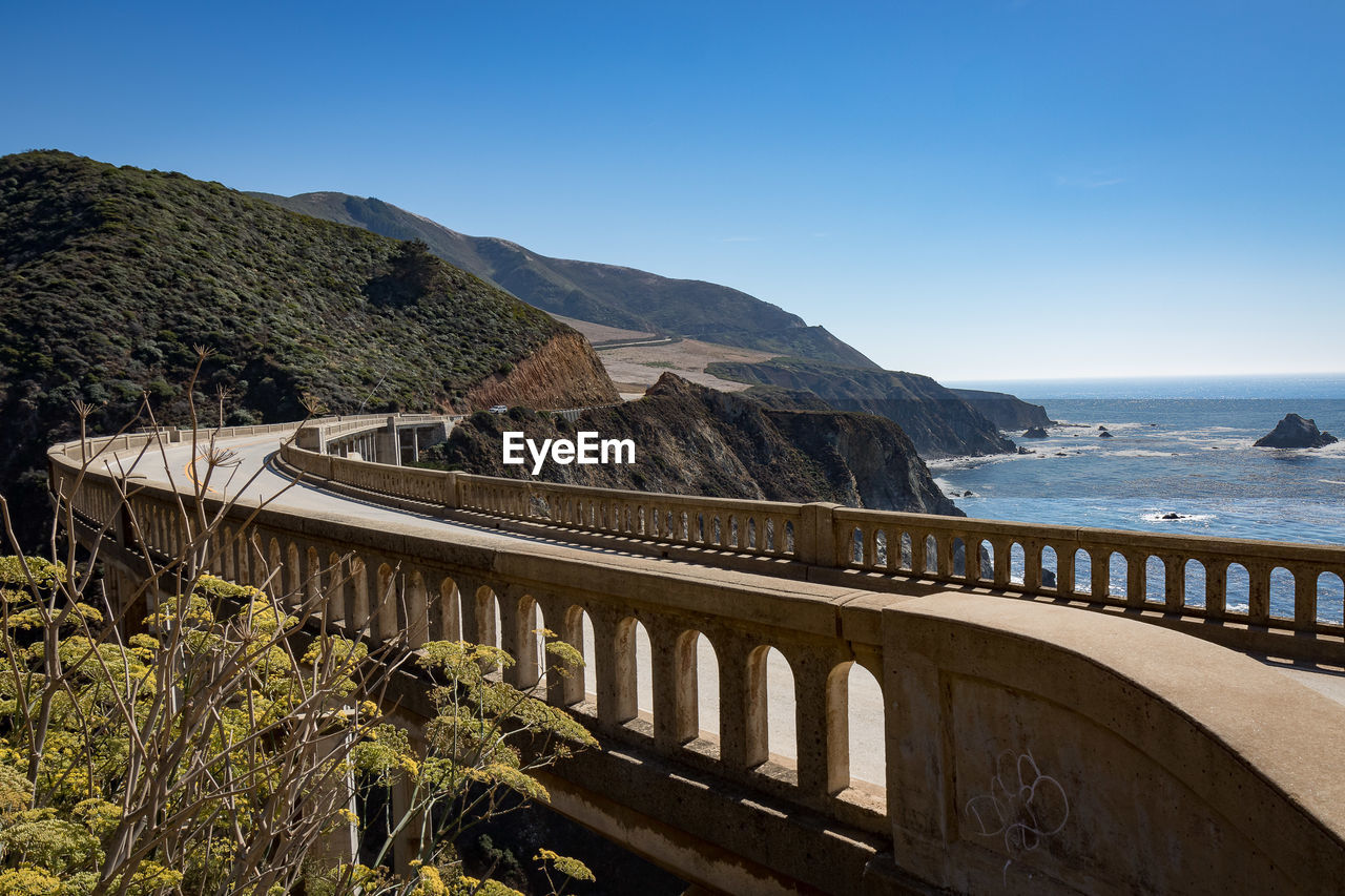 Bridge over sea against clear blue sky