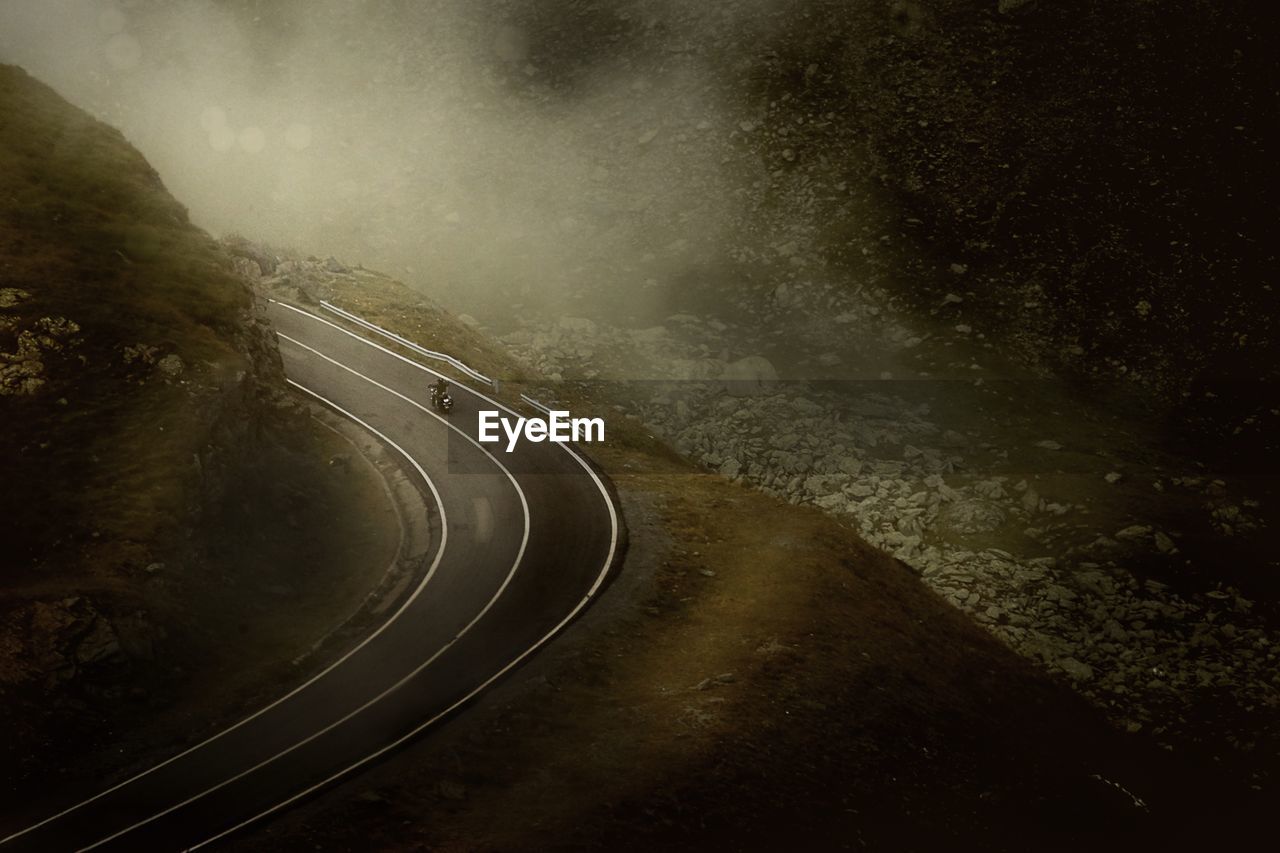 High angle view of man riding motorcycle on road in foggy weather