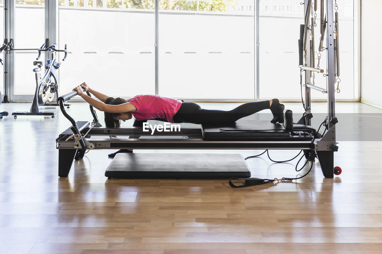 Sportswoman lying and exercising on equipment at gym