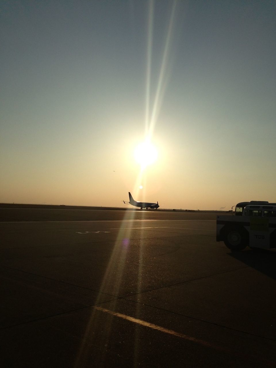 Silhouette airplane on airport runway against sunset sky