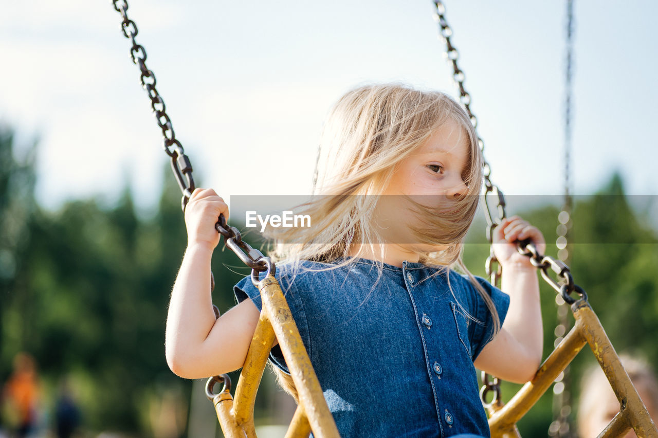 Close-up of girl holding swing in playground