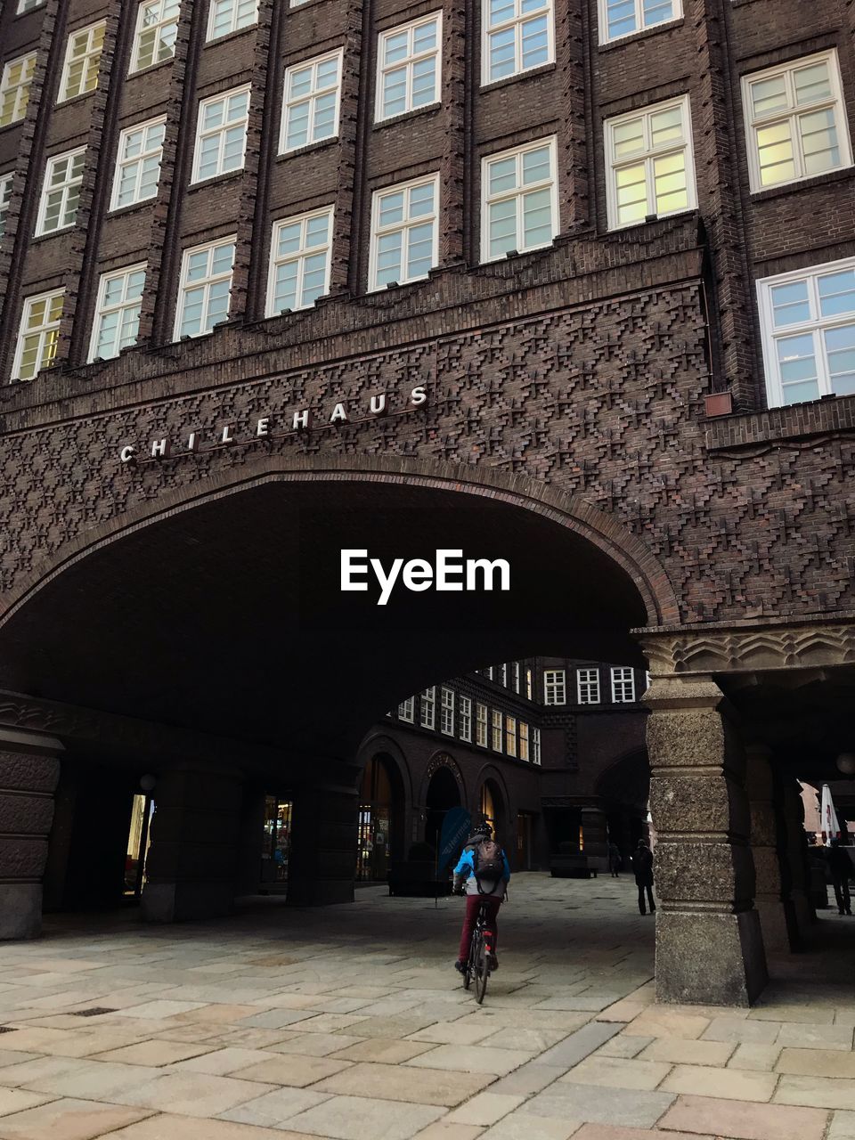 WOMAN WALKING ON STREET AMIDST BUILDINGS