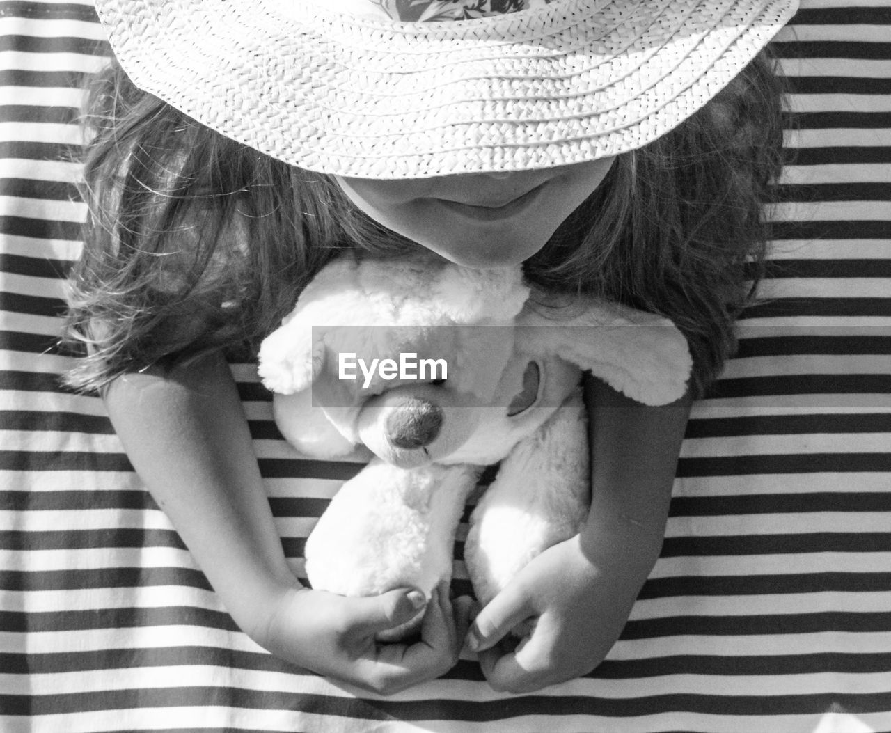 High angle view of girl with teddy bear lying down on picnic blanket