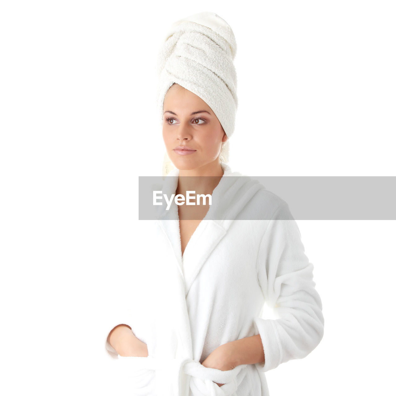 Young woman in bathrobe and towel on head against white background