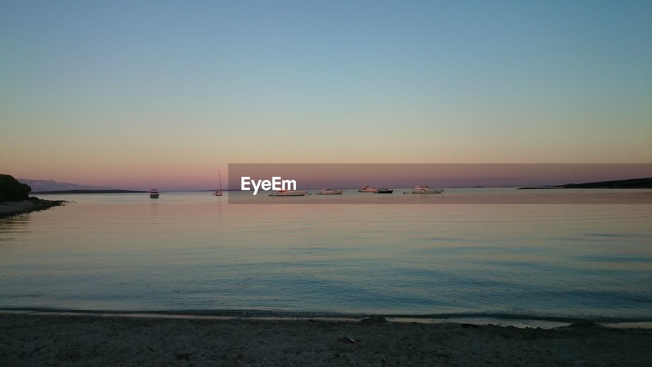 Boats in calm sea at sunset