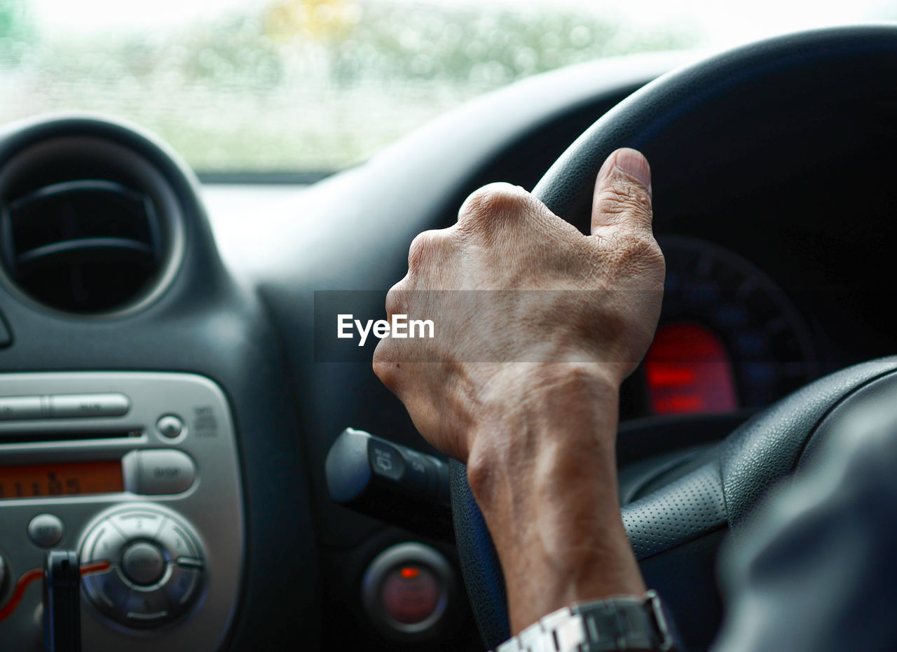 Cropped hand of man driving car