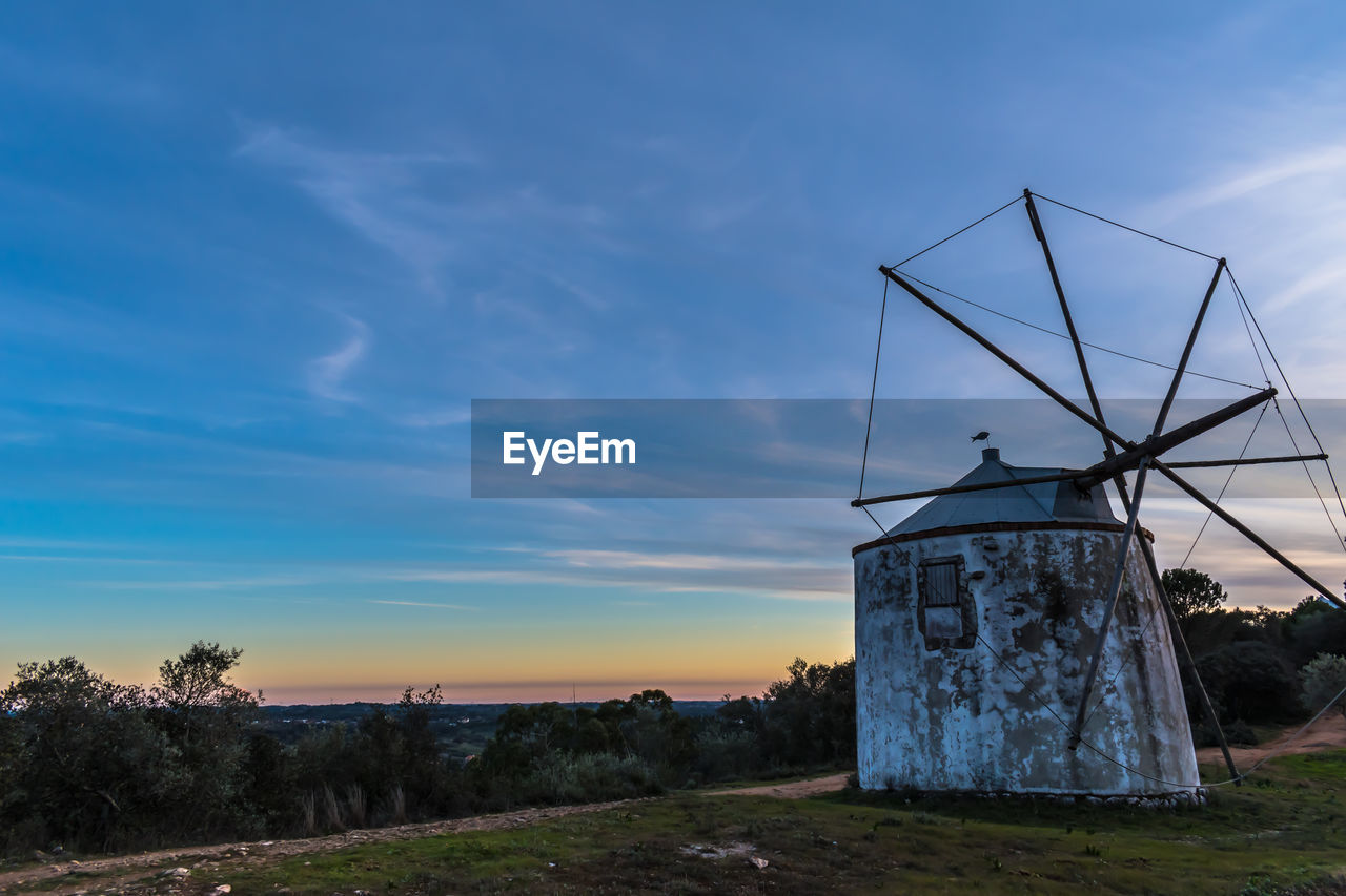 Traditional windmill on field against sky at sunset