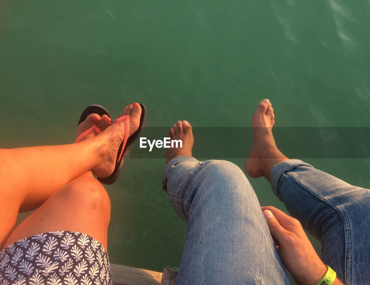 LOW SECTION OF FRIENDS SITTING ON LAKE