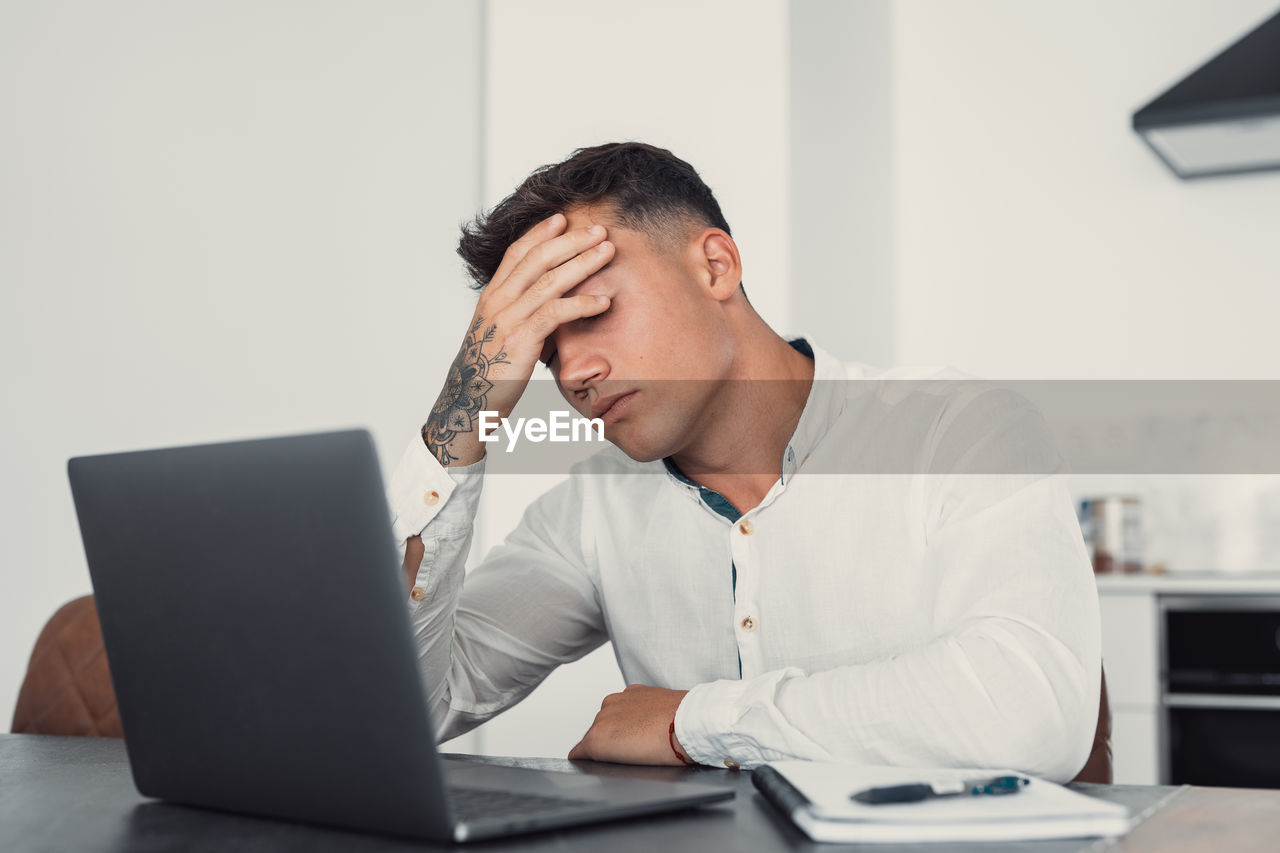side view of man using laptop at desk in office