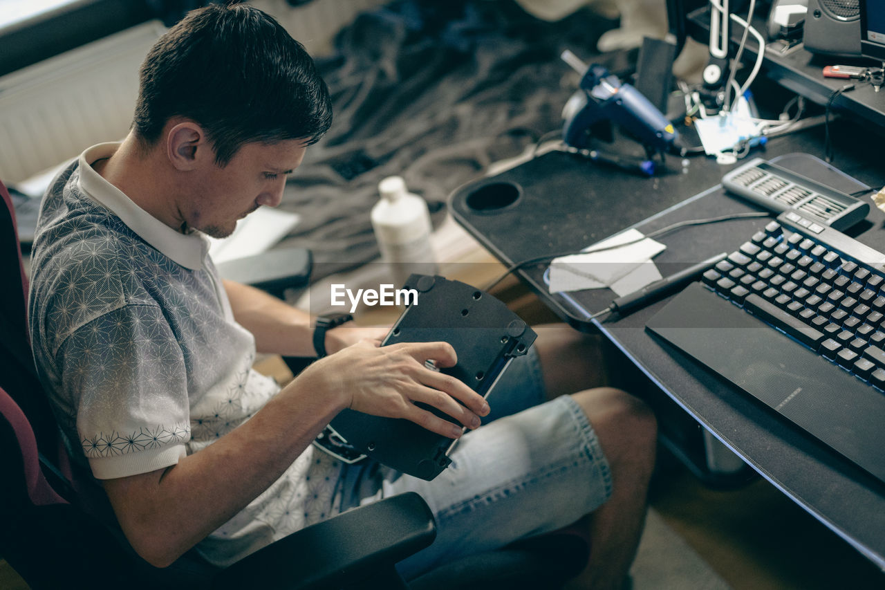 A young man repairs the engine steering wheel on a joystick.