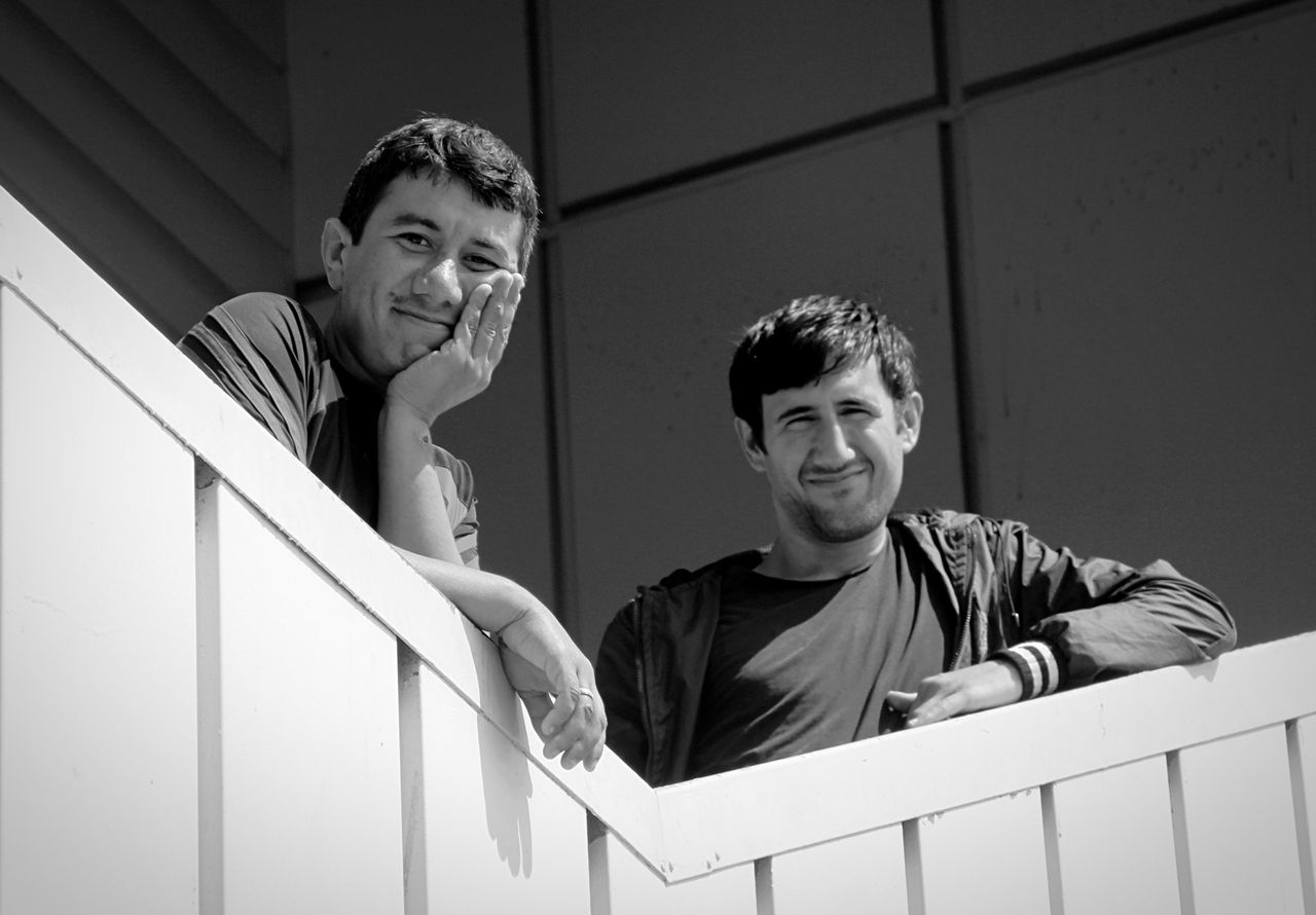 Low angle portrait of smiling friends standing by railing