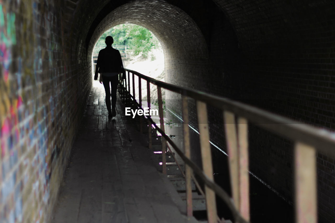 Rear view of woman walking in tunnel