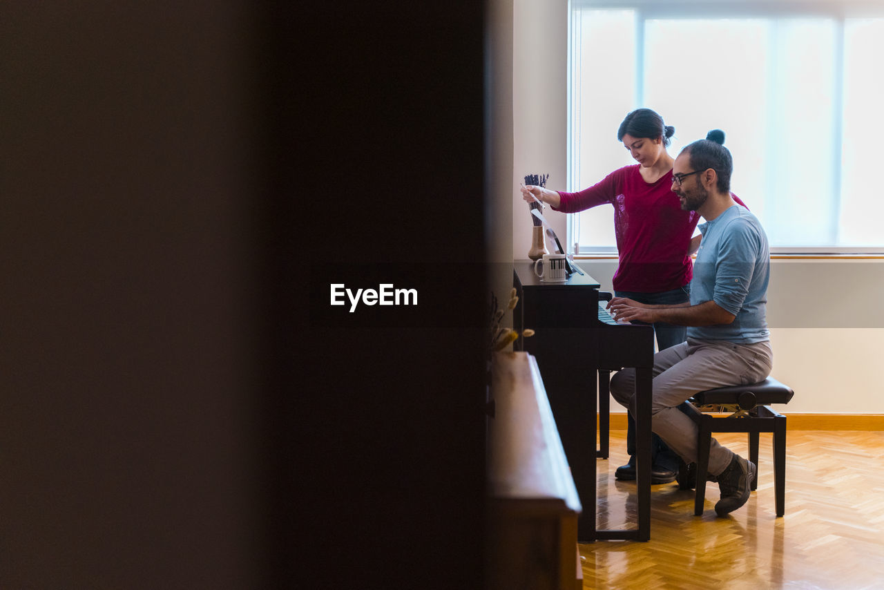 Man and woman using piano at home