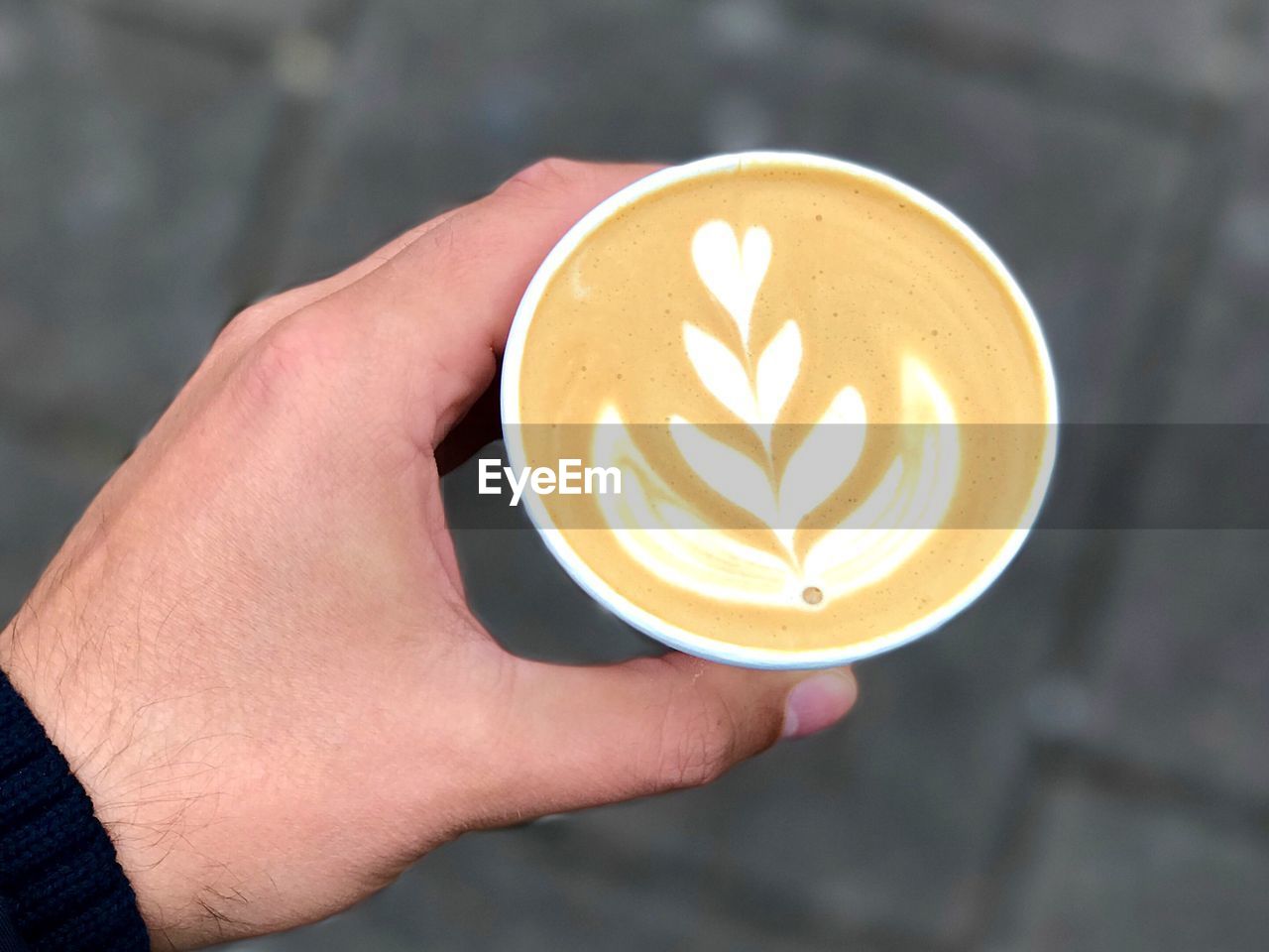 Cropped hand of man holding cappuccino with froth art