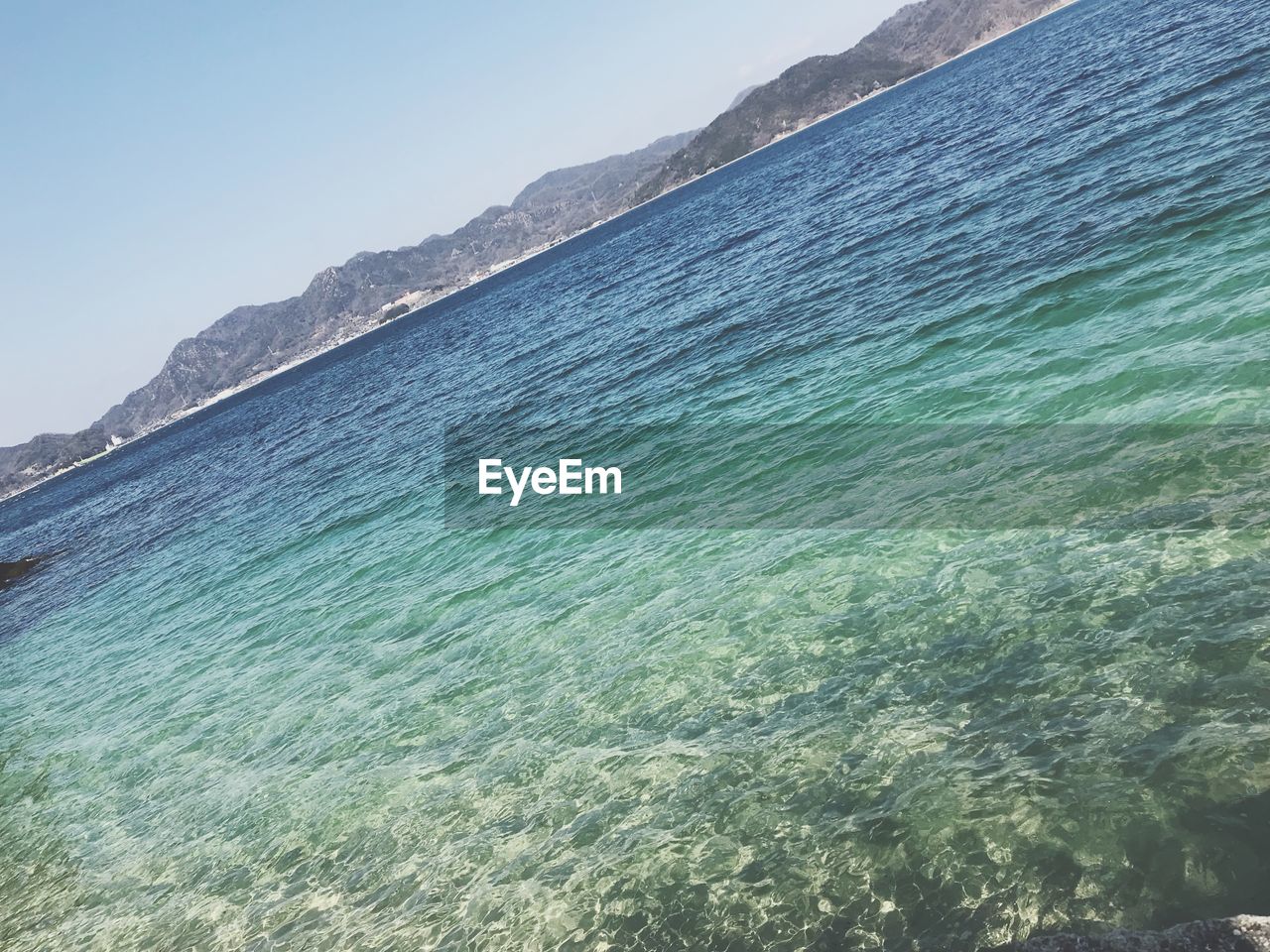 SCENIC VIEW OF SEA AND MOUNTAINS AGAINST CLEAR SKY