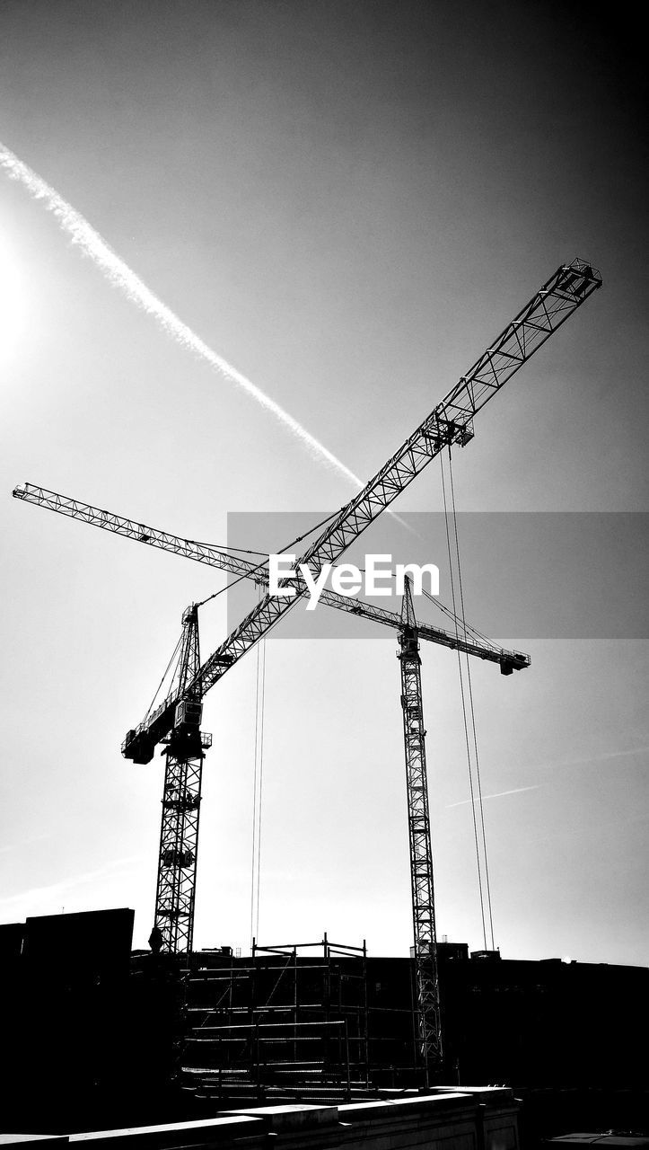 LOW ANGLE VIEW OF CRANES AGAINST SKY