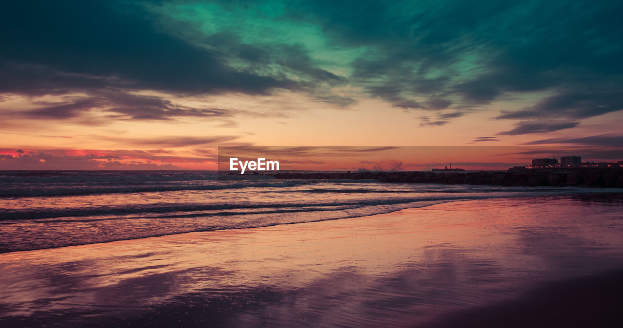 Scenic view of sea against dramatic sky during sunset