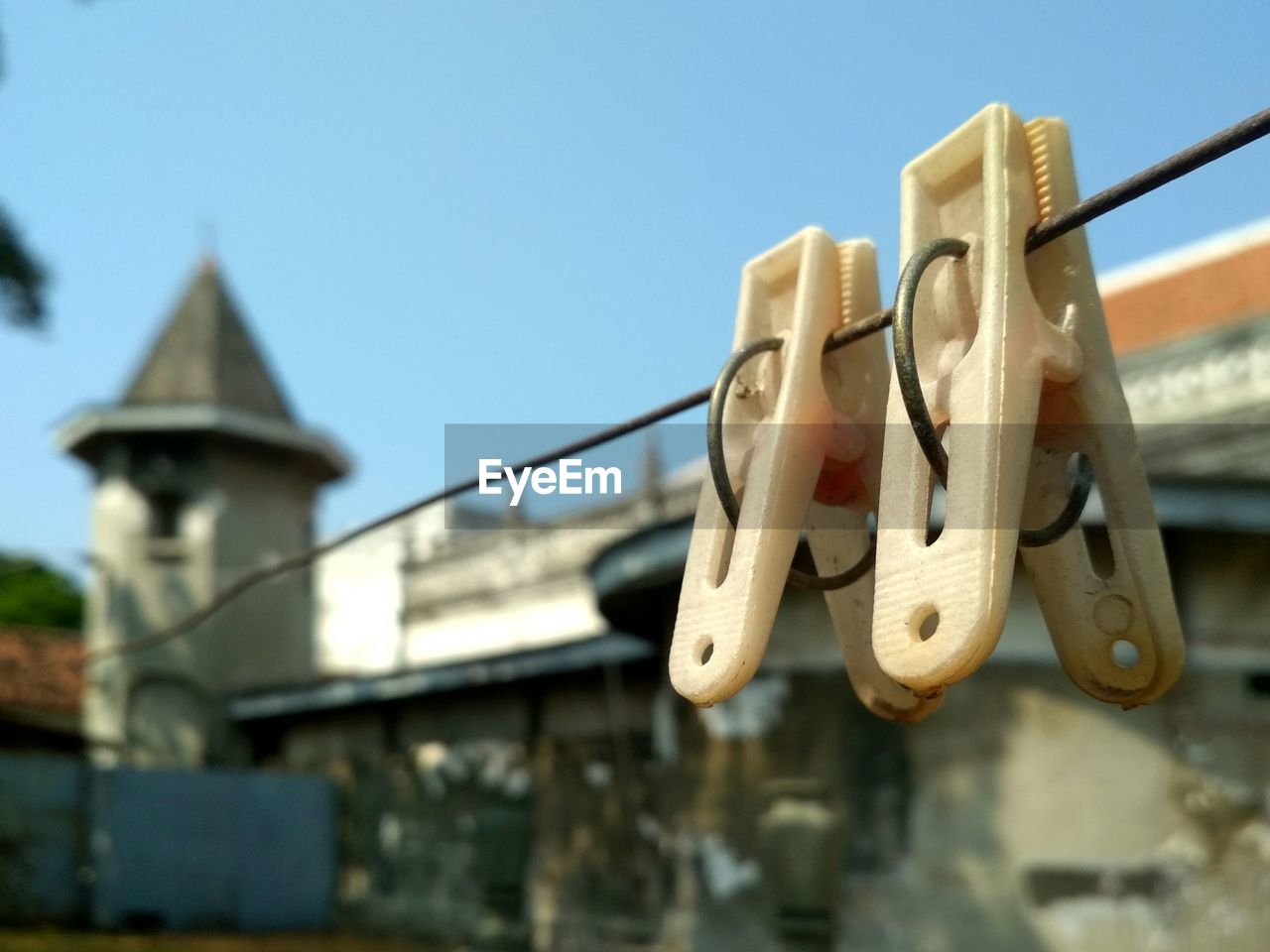 Low angle view of clothespins hanging on rope against buildings and sky
