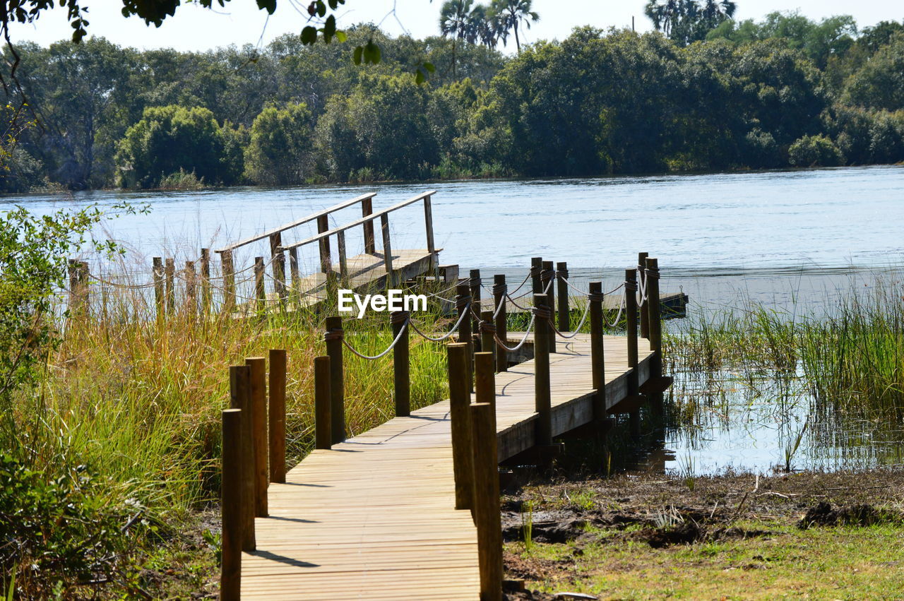 Wooden posts on footpath by lake