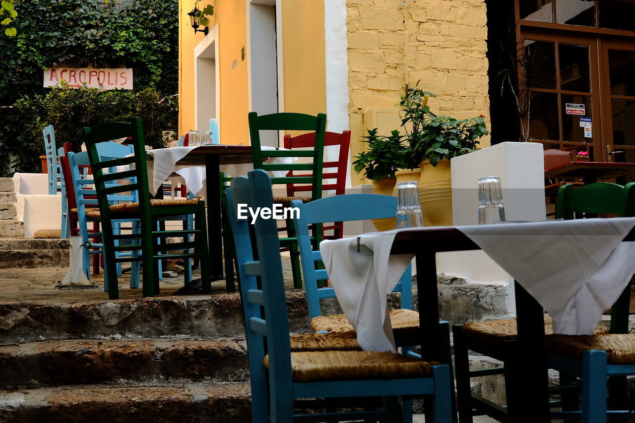 EMPTY CHAIRS AND TABLE IN RESTAURANT AGAINST BUILDING