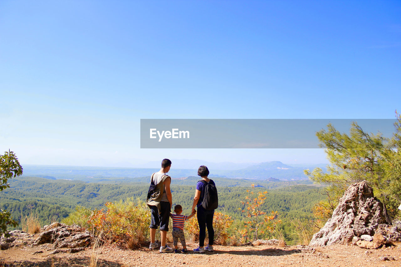 MEN ON LANDSCAPE AGAINST BLUE SKY