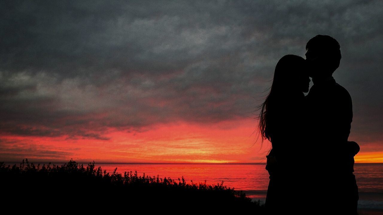 Couple embracing on sea shore at sunset