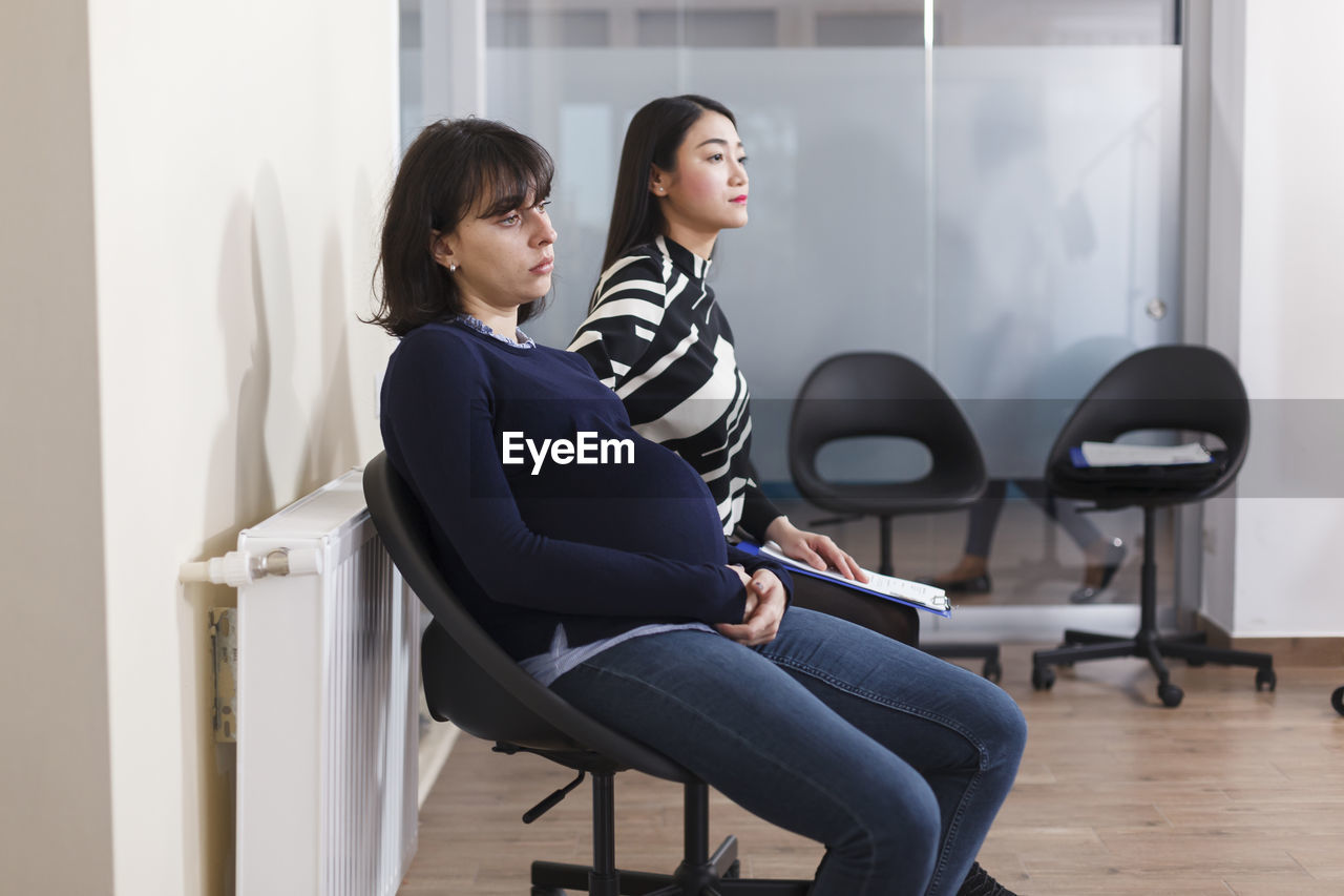 Side view of pregnant woman sitting on chair