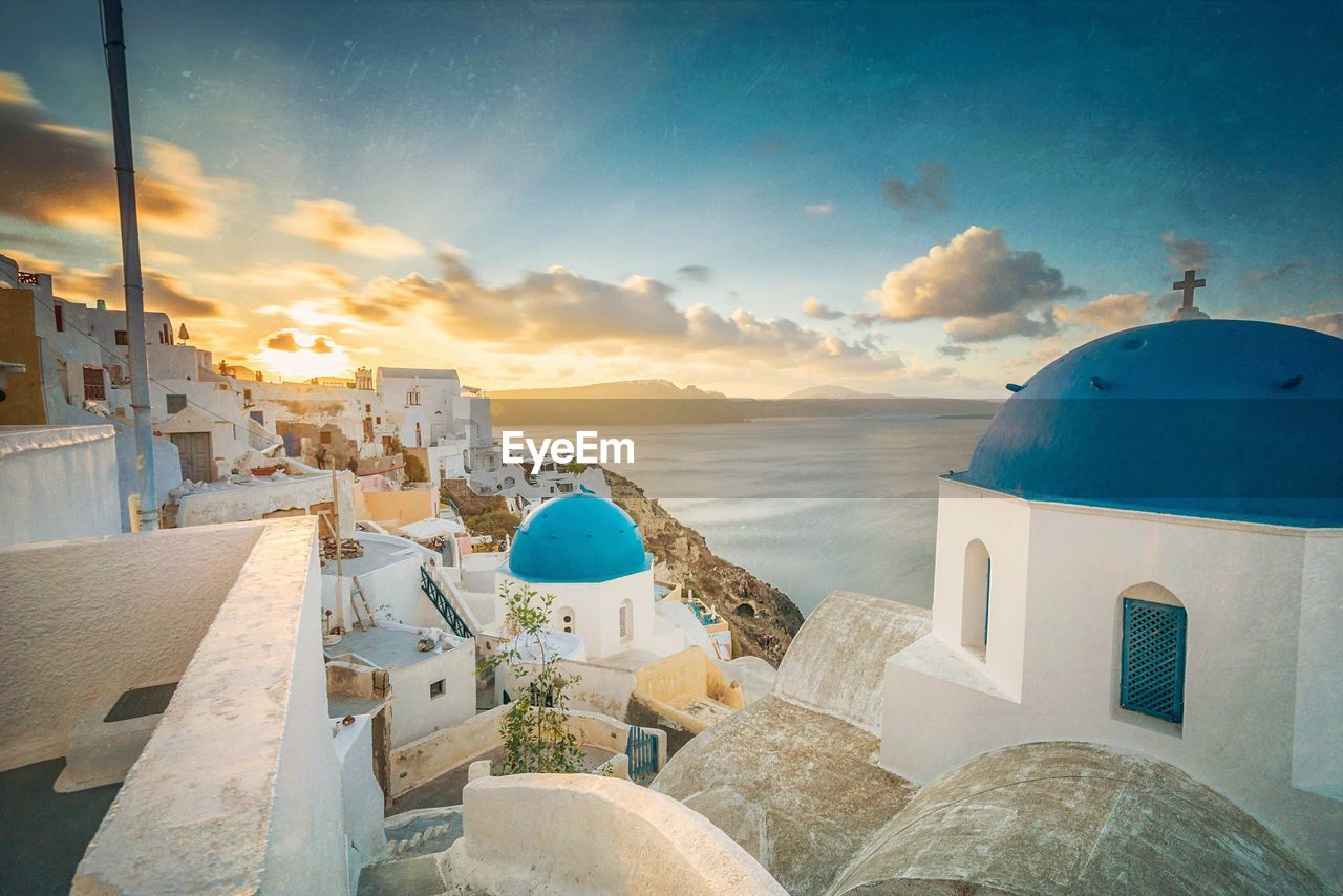 Church and houses in town by sea at santorini during sunrise