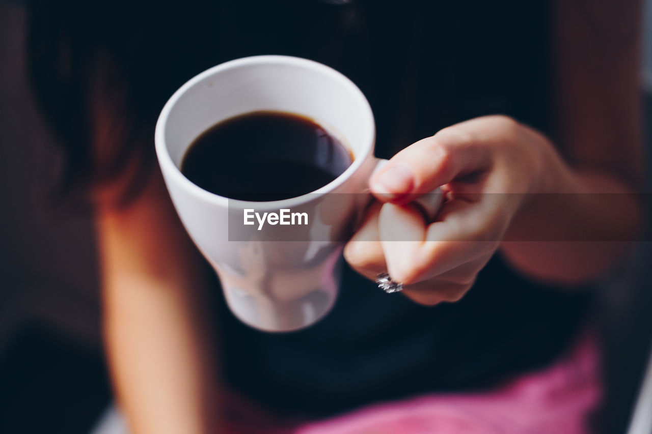 Midsection of woman holding coffee cup