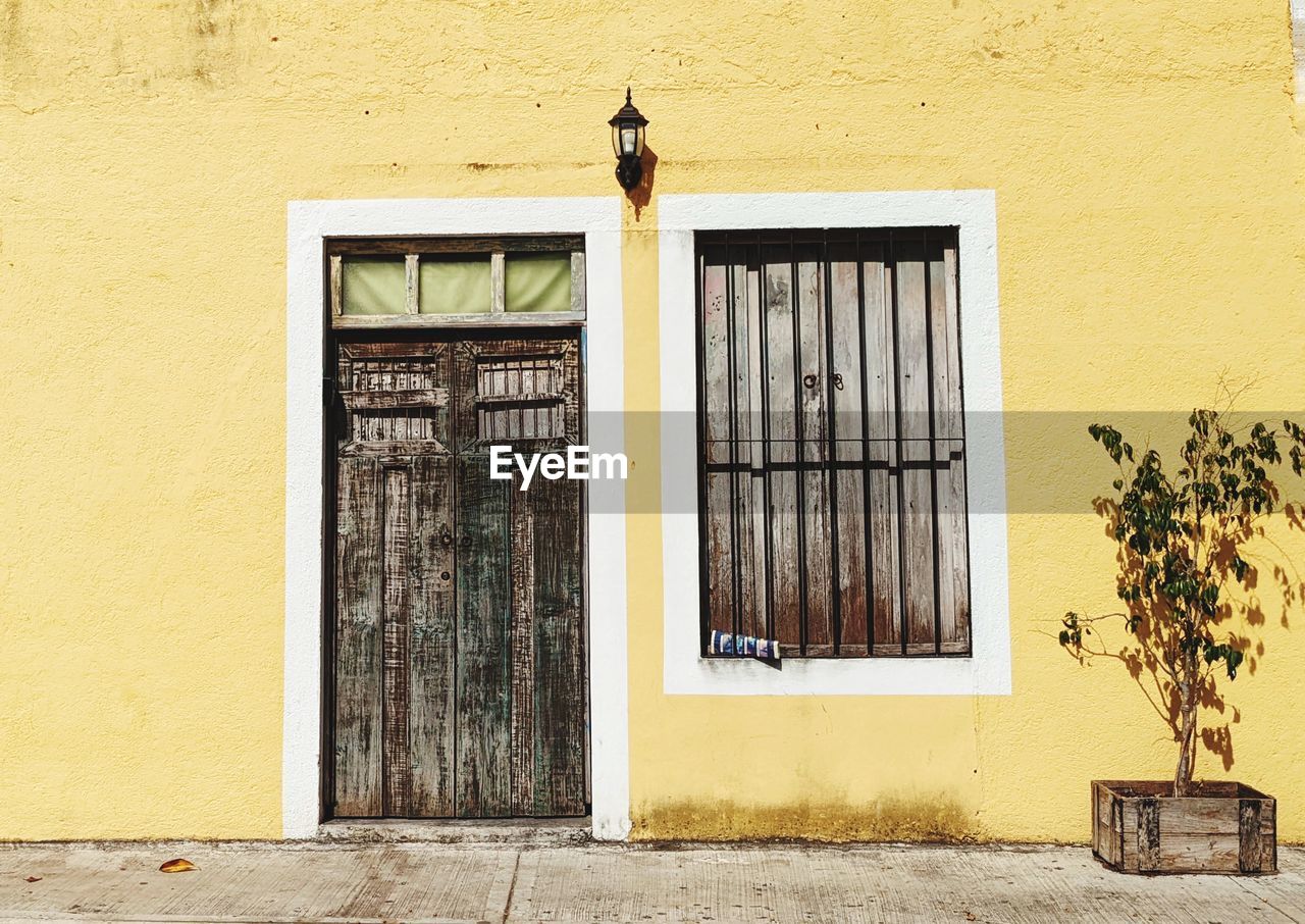 A closed window and door on a yellow wall