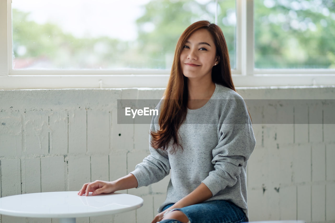 Portrait of smiling woman sitting by window