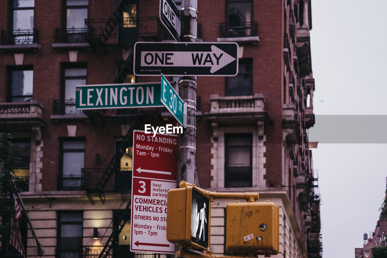 Low angle view of road sign against buildings in city