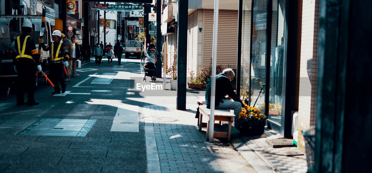 PEOPLE WALKING ON FOOTPATH BY CITY STREET