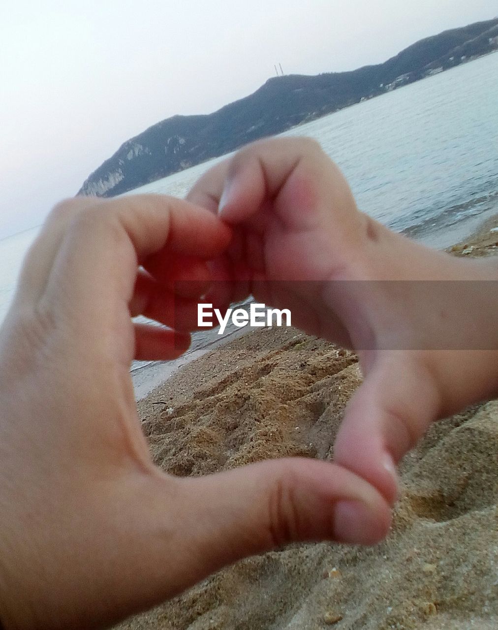 CLOSE-UP OF COUPLE KISSING AGAINST SEA