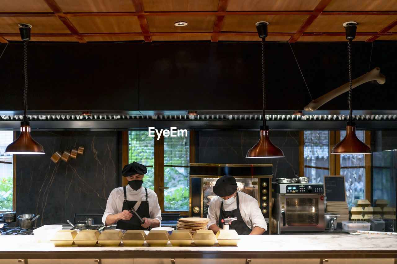 Chefs wearing protective face mask standing in restaurant