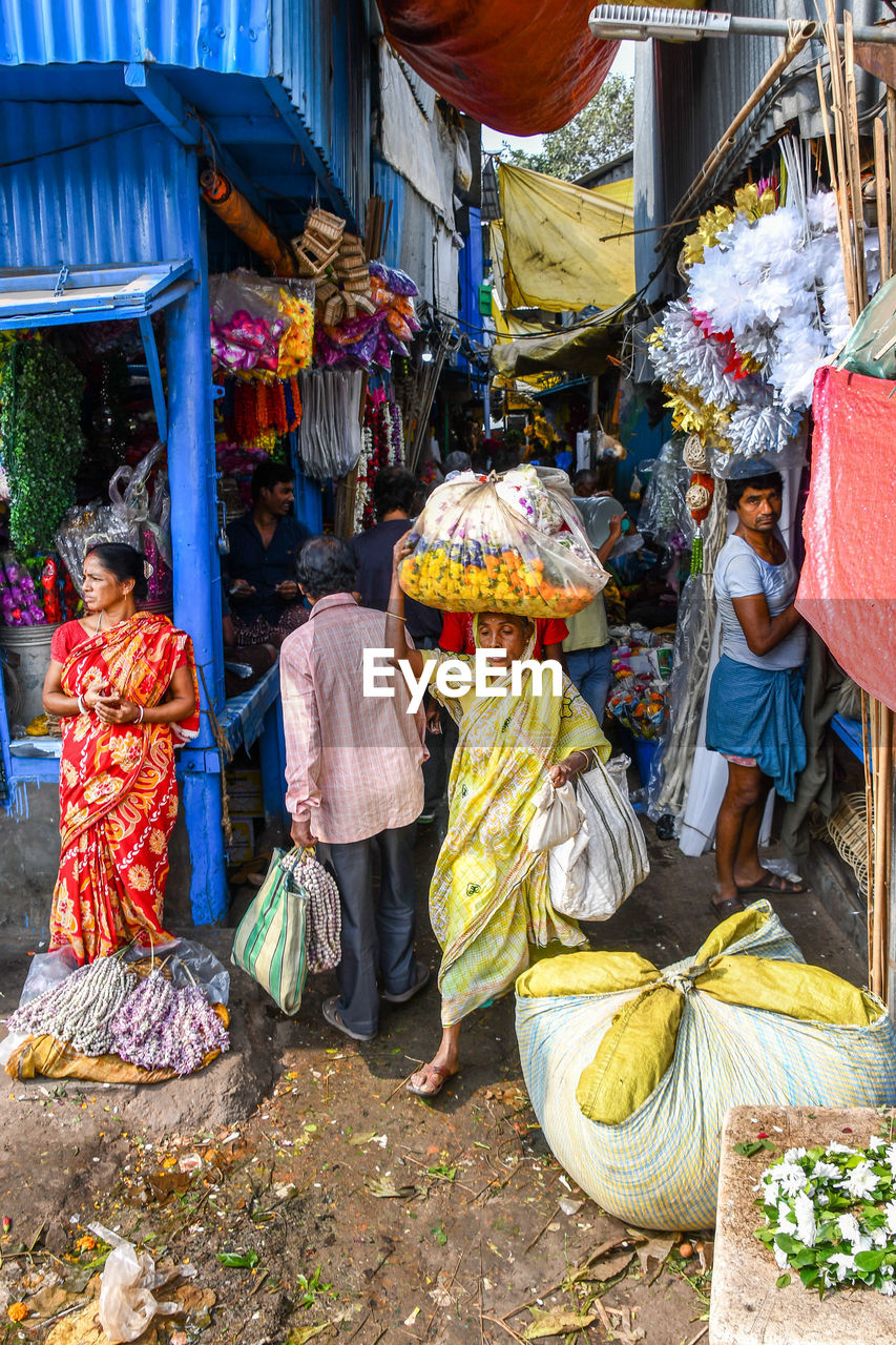 GROUP OF PEOPLE AT MARKET STALL IN CITY