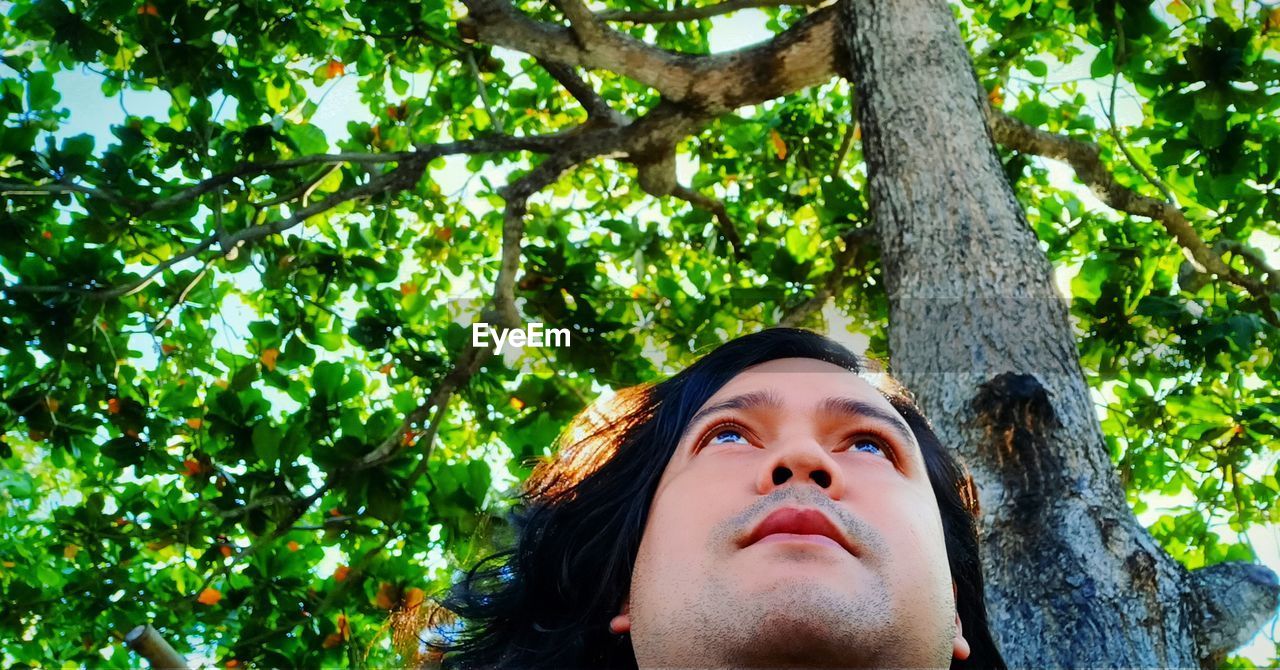 Portrait of a person deep in his thoughts looking away against tree trunk