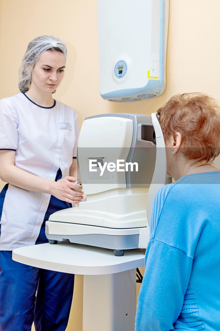 A girl optometrist examines the eyes of a patient using special modern equipment