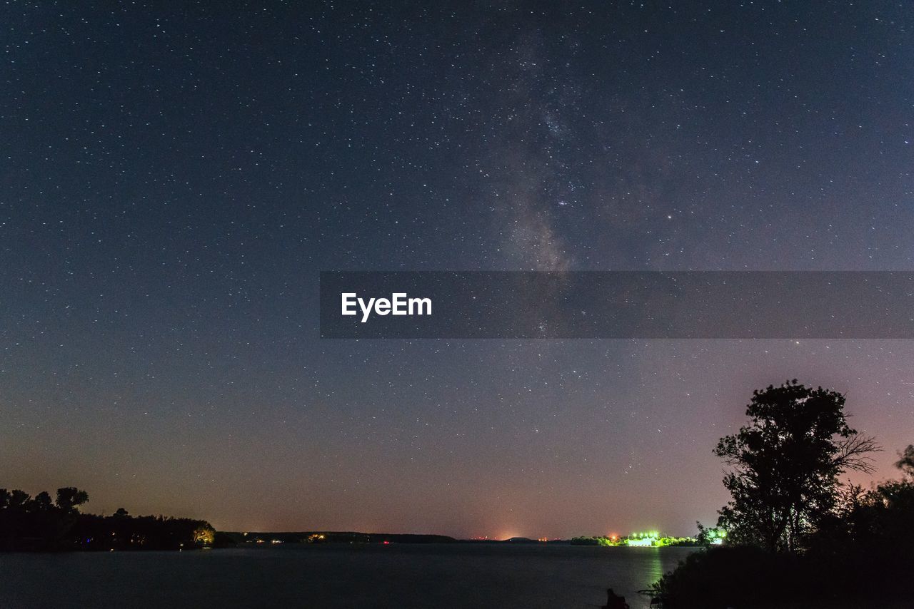 LOW ANGLE VIEW OF SILHOUETTE TREES AGAINST STAR FIELD AGAINST SKY