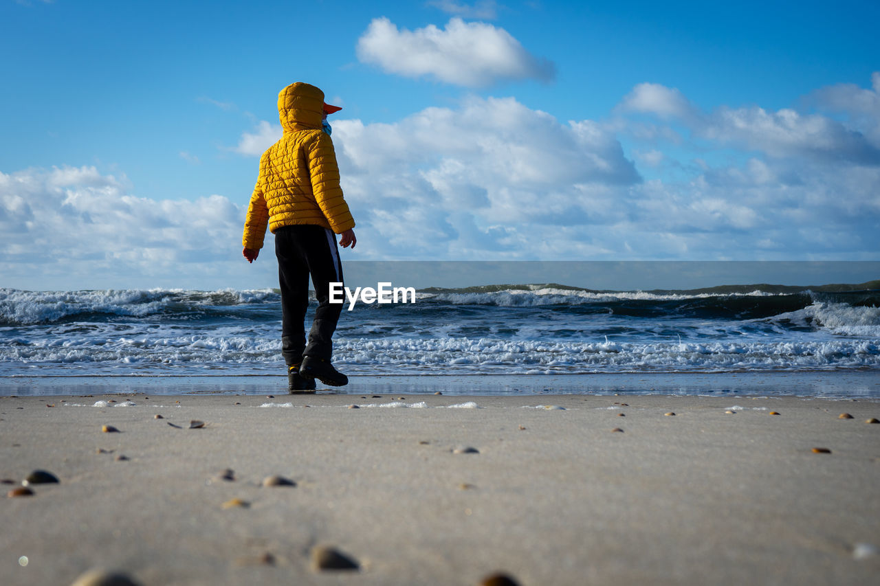 Full length of man standing on beach against sky