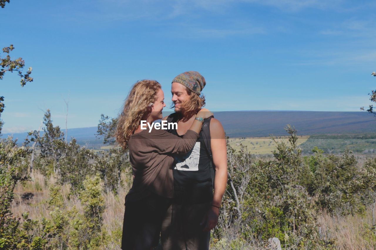 Happy couple standing on mountain against blue sky