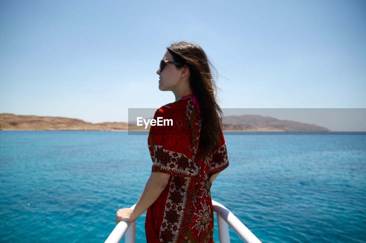 Rear view of young woman standing on yacht bow sailing on red sea