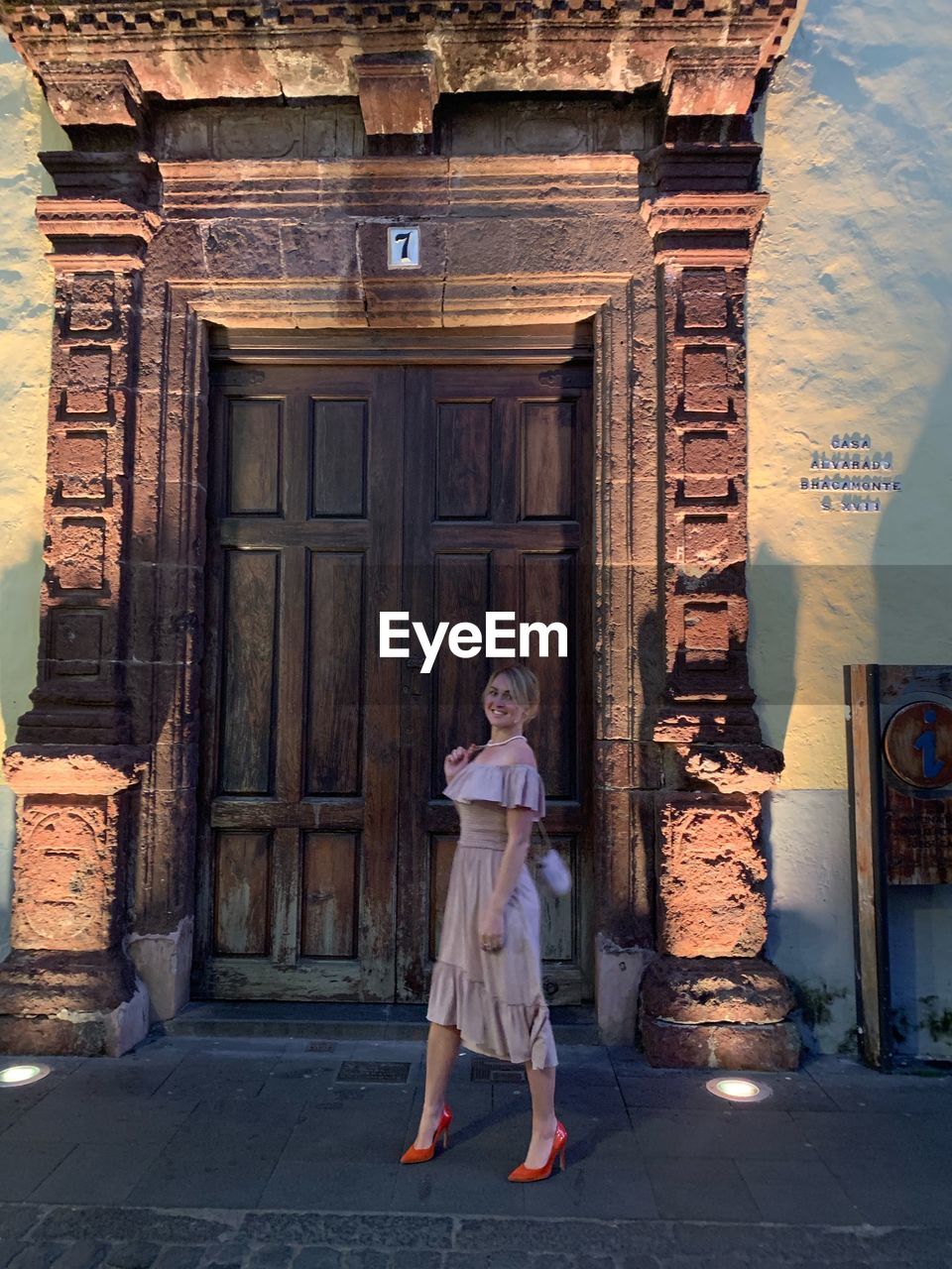 PORTRAIT OF WOMAN STANDING AGAINST BUILDING