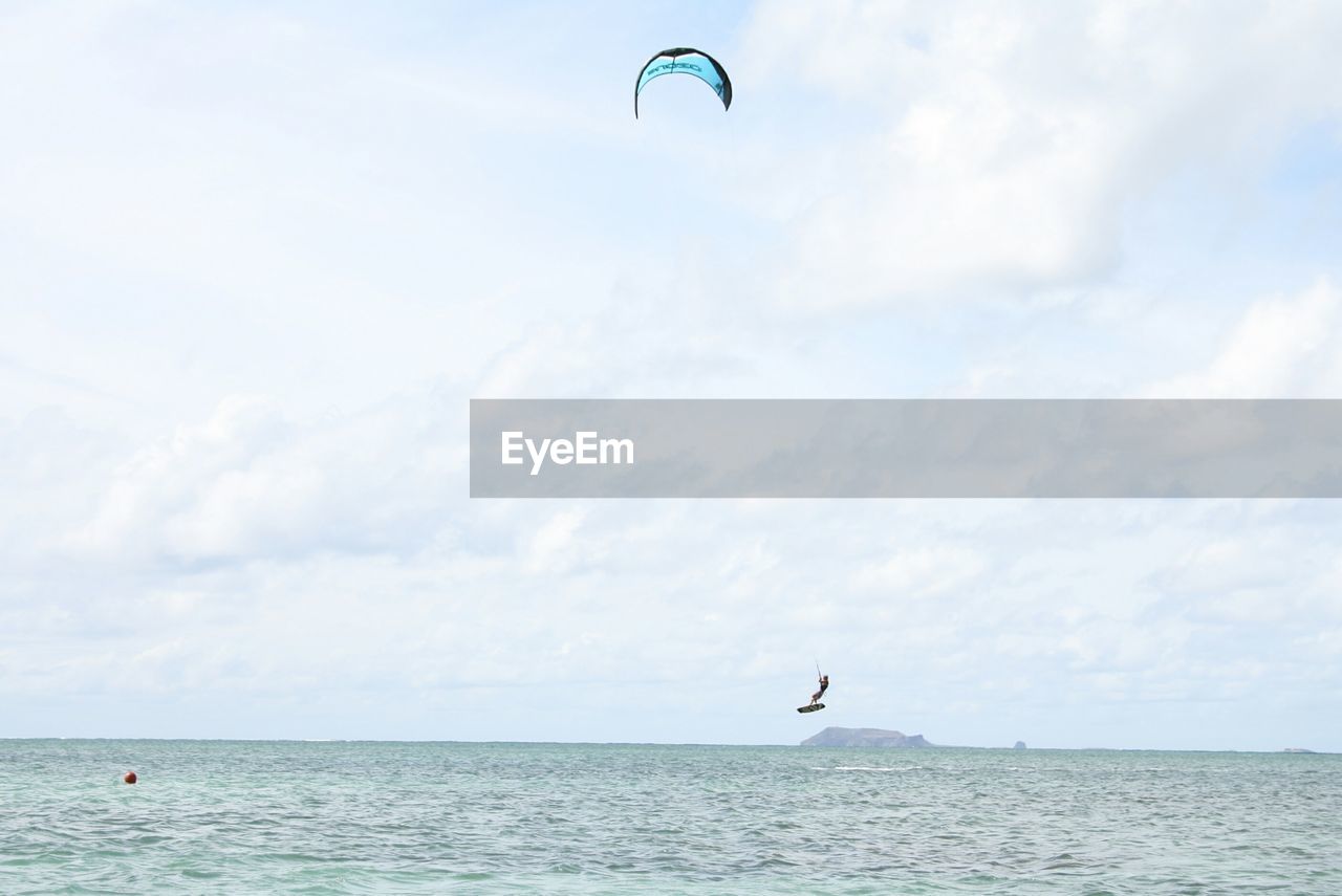 MAN FLYING OVER SEA AGAINST SKY