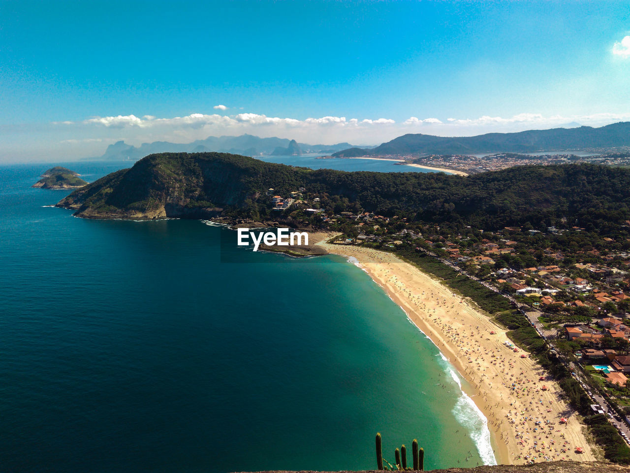 Aerial view of sea and mountains against blue sky