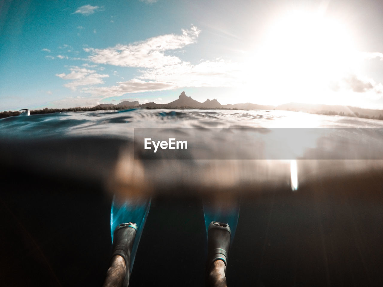 Low section of person in sea against sky