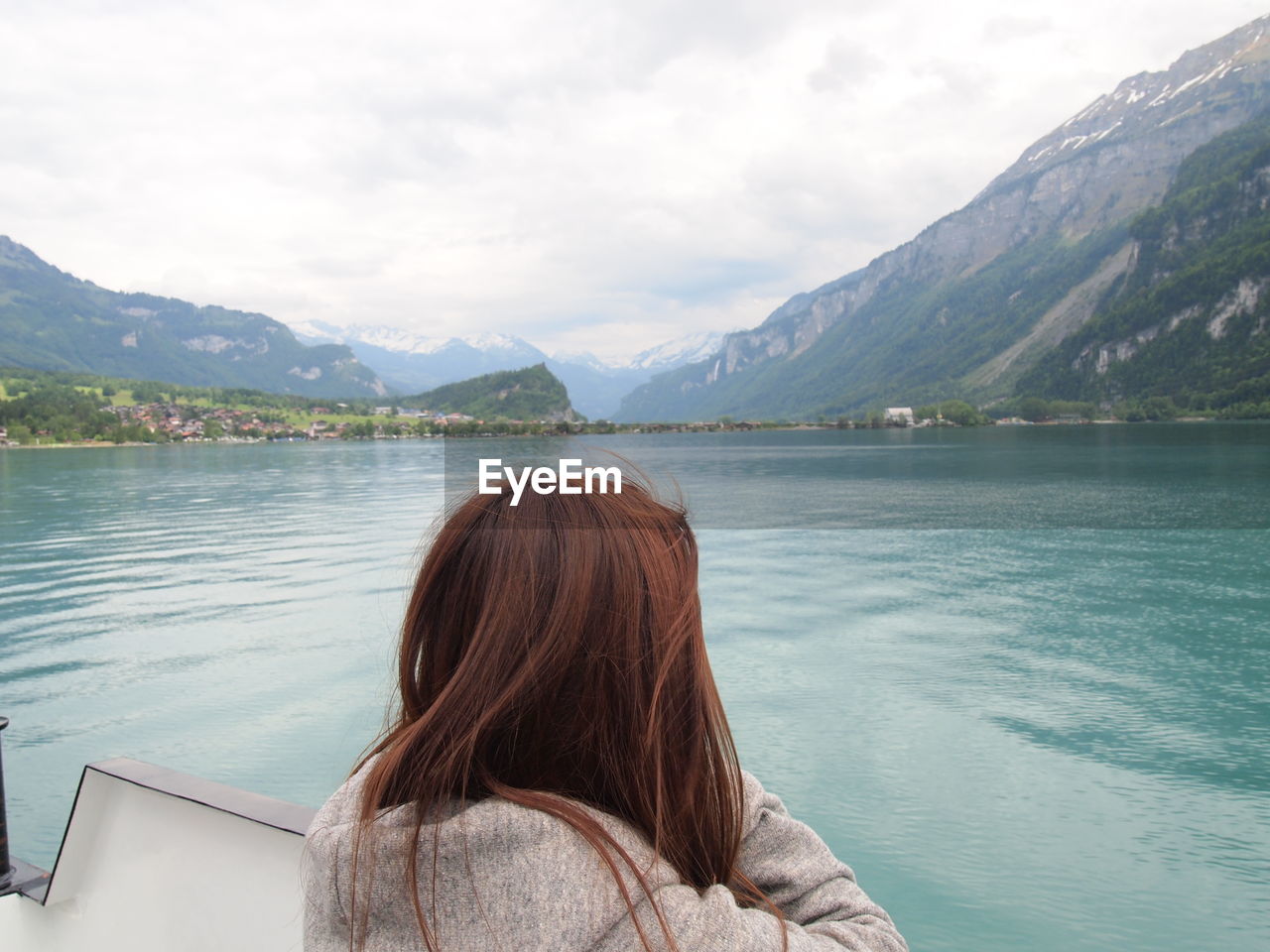 Rear view of woman looking away while standing by lake