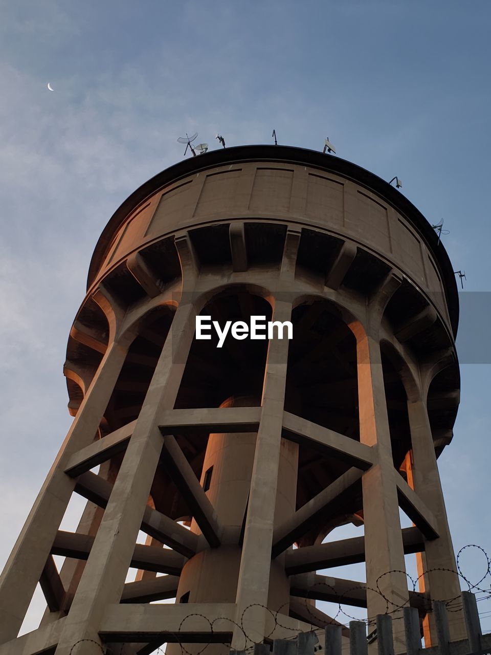 LOW ANGLE VIEW OF WATER TOWER AGAINST SKY SEEN THROUGH METAL BRIDGE