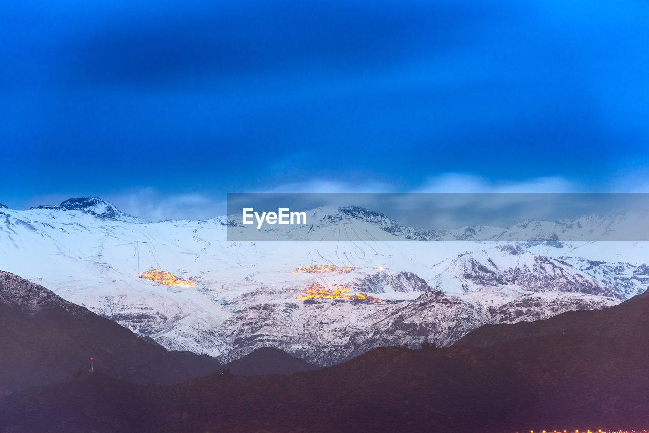 AERIAL VIEW OF SNOWCAPPED MOUNTAINS AGAINST BLUE SKY